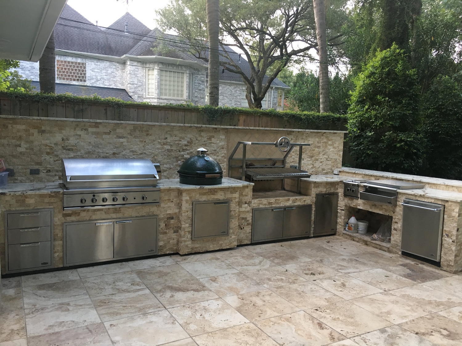 outdoor kitchen with a stone countertop featuring a grill, a green egg smoker, and stainless steel cabinets