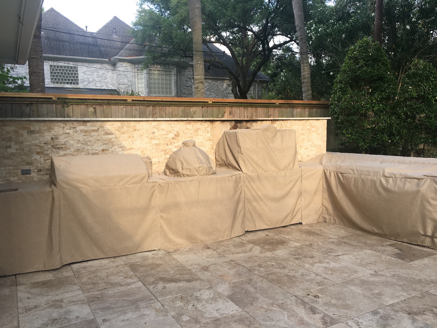 outdoor kitchen with a stone countertop featuring a grill, a green egg smoker, and stainless steel cabinets with custom cover