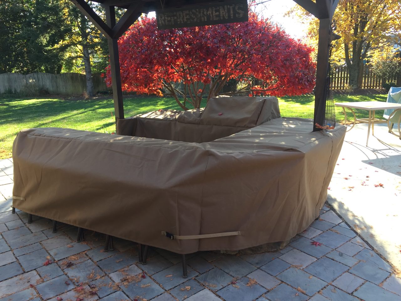 An outdoor island covered with a custom cover sits under an umbrella
